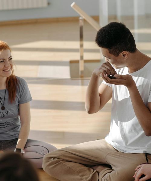Diverse group of people smiling during a light yoga practice in a bright studio.